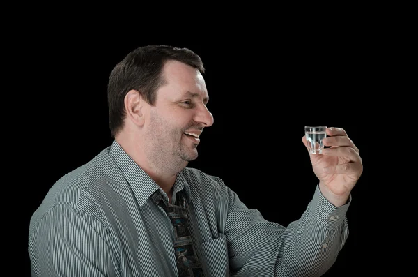 Smiling guy holds shot of vodka — Stock Photo, Image
