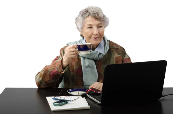 Vieja bebiendo café mientras lee noticias en su leptop — Foto de Stock