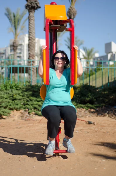 Mujer haciendo entrenamiento de fitness en una máquina de mariposa al aire libre — Foto de Stock