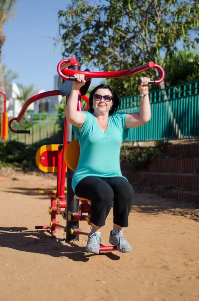 Woman enhancing her arms in fitness station — Stock Photo, Image
