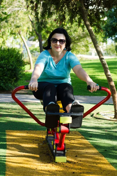 Mujer haciendo ejercicio en una estación de remo al aire libre — Foto de Stock