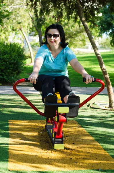 Mature femme formation sur la machine à ramer en plein air — Photo