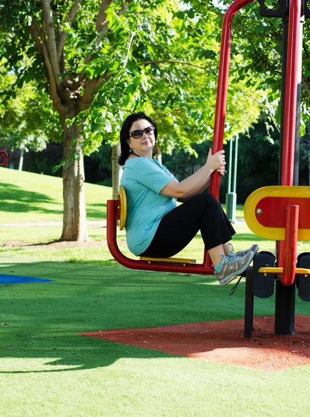 Mature woman bending her legs on the leg press station outdoor — Stock Photo, Image