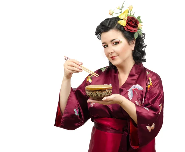 Kimono vrouw uit een kom eten met stokjes — Stockfoto