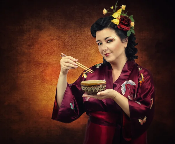 Flowers haired kimono woman eating with chopsticks — Stock Photo, Image