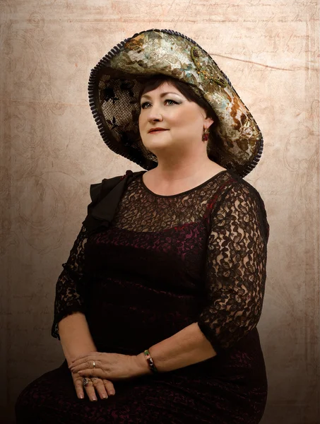 タペストリーの帽子の成熟した女性 — ストック写真