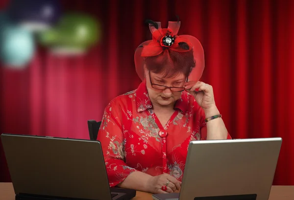 Mujer madura en sombrero mirando la pantalla de la computadora — Foto de Stock