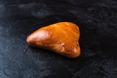 Karanlık bir masada taze pişmiş lezzetli çörek. Pastaneden gelen lezzetli pişmiş yiyecekler. Siyah arkaplan.