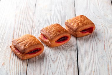 Beyaz ahşap bir masada taze pişmiş lezzetli çörek. Pastaneden gelen lezzetli pişmiş yiyecekler. Beyaz arkaplan.