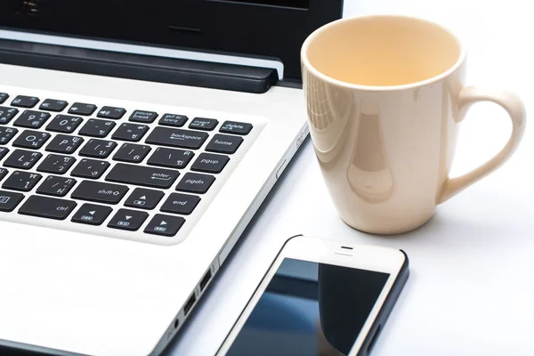 Fermer tasse de café avec ordinateur portable et téléphone cellulaire isolé sur blanc — Photo