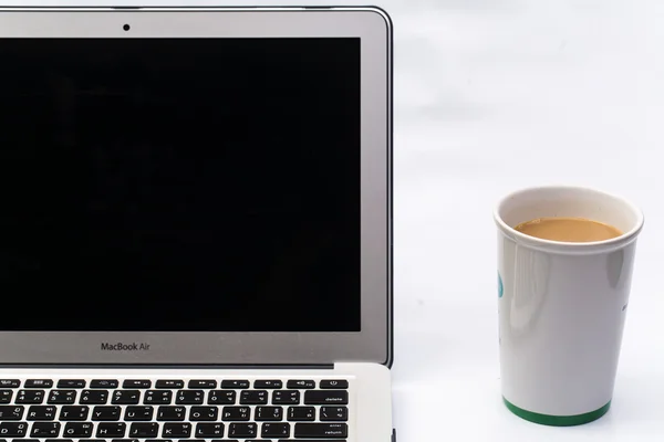 Mesa de trabalho branca com computador portátil, uma chávena de café — Fotografia de Stock