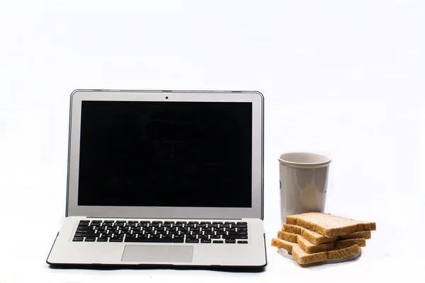 Computador portátil, um copo de café e pão — Fotografia de Stock