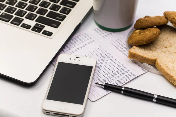 Laptop com celular, banco de livros, biscoito, pão e xícara de coff — Fotografia de Stock