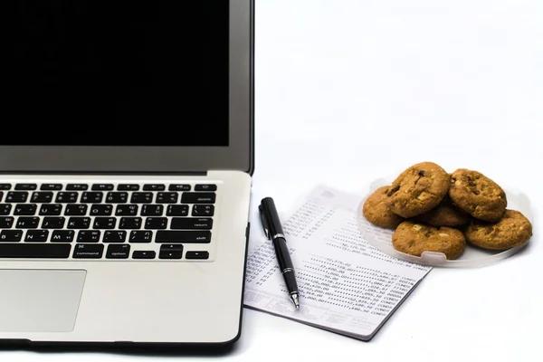 Escritório com computador portátil, banco de livros e cookie — Fotografia de Stock