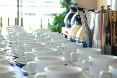 Kahve fincanı sehpanın üzerinde kavanozdan kahve dökülüyor.