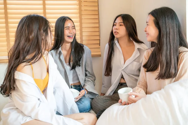 Women group talking on cozy white bed in morning with coffee cup friendship group