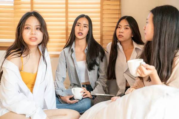 Women group talking on cozy white bed in morning with coffee cup friendship group