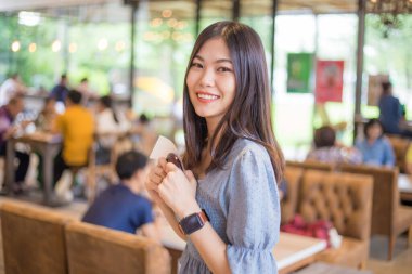 Kafede kahve siparişi bekleyen güzel Asyalı kadınlar arka plandaki insanları bulanıklaştırdı.