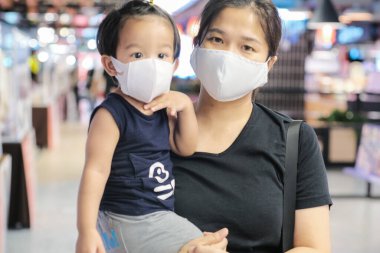 Anne kucağında çocuk süpermarkette maske alışverişi yapıyor.