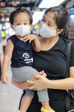 Anne kucağında çocuk süpermarkette maske alışverişi yapıyor.