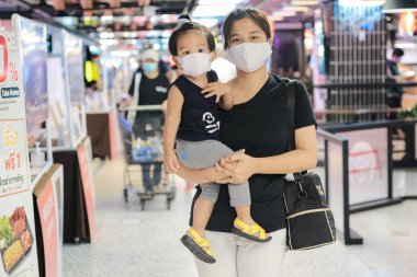 Anne kucağında çocuk süpermarkette maske alışverişi yapıyor.
