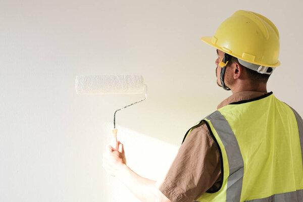 Painter man holding with painting roller in white room new house concept