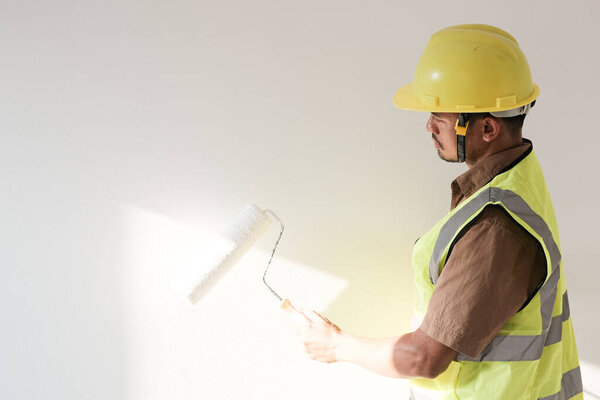 Painter man holding with painting roller in white room new house concept