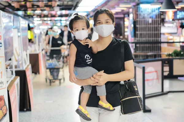 Mom hold boy wear mask shopping in supermarket healthy concept