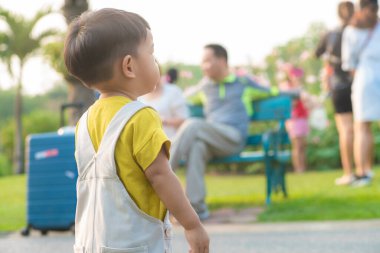 Küçük çocuk hafta sonu tatili için şehir parkında akşam vakti ağaç yemyeşil çimlerde yürüme alıştırması yapıyor.