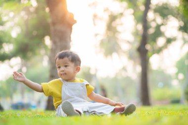 Çok tatlı bir bebek çocuk oynuyor. Yol kenti parkının gün batımı ışığı yeşil ağaç zeminli