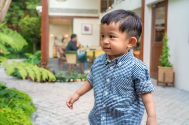 Sevimli erkek bebek bahçede yürüyor. Doğada yeşil ağaç çocuk.