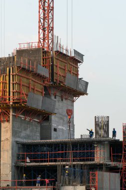 İnşaat mühendisi ve mekanik ekip inşaat halindeki vinç ve binalarla çalışıyor.