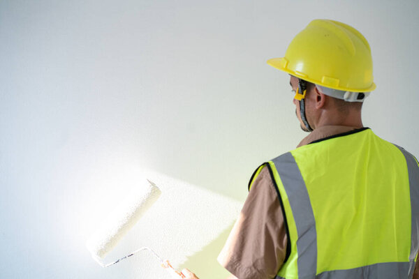 Mechanical painter man painting white color interior new house building with copyspace
