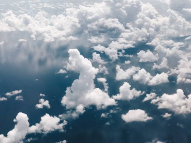 Mavi gökyüzü ve uçak penceresinden bulutlu manzara.