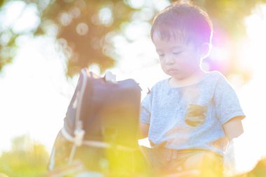 Parkta yeşil çimlerde oynayan sevimli küçük çocuk. Gün batımı doğada hafif çocuk.