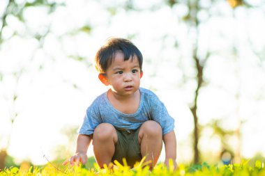Parkta yeşil çimlerde oynayan sevimli küçük çocuk. Gün batımı doğada hafif çocuk.