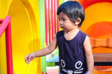 Neşeli, tapılası 1-2 yaşındaki küçük çocuk şehir parkında eğleniyor, Oğlan renkli kaydırma oynuyor.