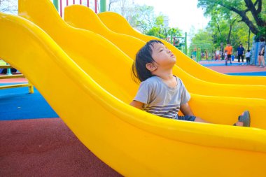 Neşeli, tapılası 1-2 yaşındaki küçük çocuk şehir parkında eğleniyor, Oğlan renkli kaydırma oynuyor.