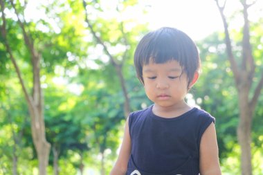 Yeşil doğa parkında küçük Asyalı bir çocuğun portresi, çocukluk sabahı gündoğumu