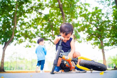 Little asian boy playing balance bike in city park sunset light boy exercise