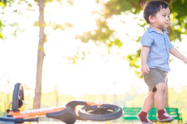 Little asian boy playing balance bike in city park sunset light boy exercise