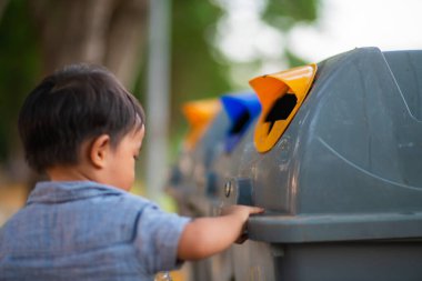 Toddler boy keep trash to bin in city park environment clean concept