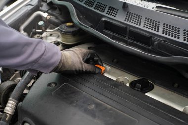Tamirci motor yağını kontrol ediyor. Arabanın bakımını yapıyor. Motoru kapat.