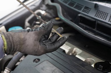 Tamirci motor yağını kontrol ediyor. Arabanın bakımını yapıyor. Motoru kapat.