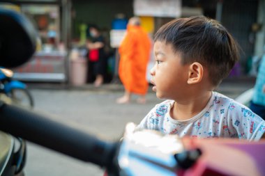 Vespa scooter 'da oturan küçük çocuk açık hava portresi yapıyor.