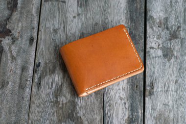 Ahşap arka planda kahverengi deri çift katlı cüzdan.