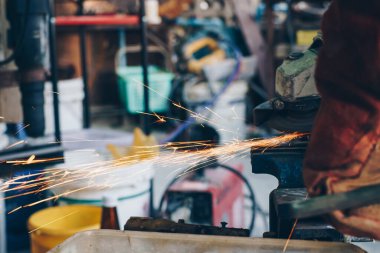 Mekanik adam, metal endüstrisinde alev kıvılcımları saçan elektrikli öğütücü kullanıyor.