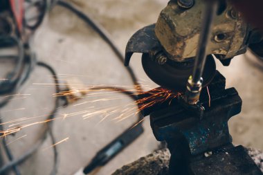 Mekanik adam, metal endüstrisinde alev kıvılcımları saçan elektrikli öğütücü kullanıyor.