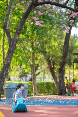 Çiçek ağacı bahçesinde sallanan at oynayan komik, sevimli, mutlu bir bebek. Mutluluğun duygusu
