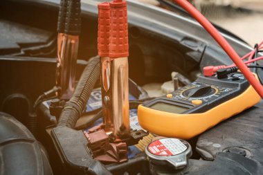 Tamirci voltaj seviyesini kontrol etmek için voltaj ölçer kullanıyor.